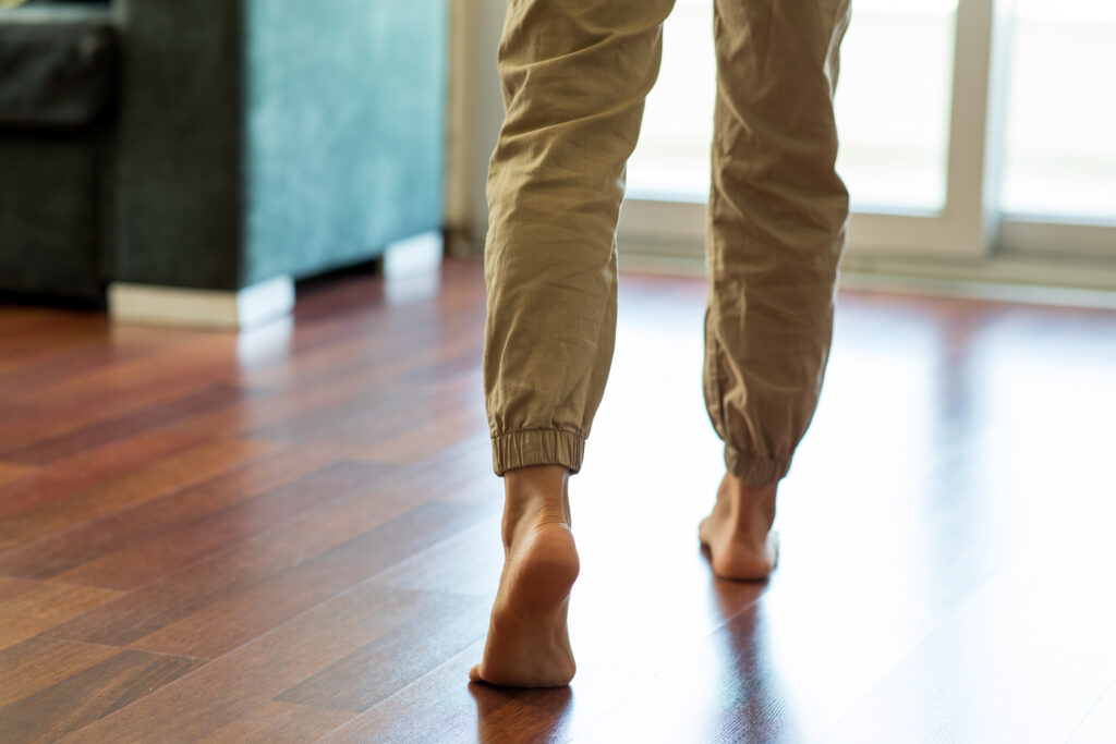 Woman legs and feet walking on floor at home