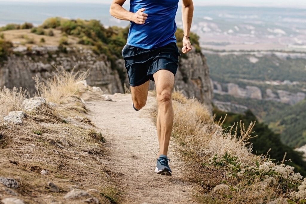 rangy male runner run on mountain trail, muscular legs man jogger athlete running narrow
